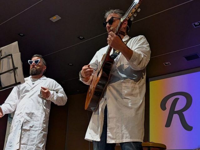 Retórico e Hipotenuso en escena, con batas blancas y guitarra