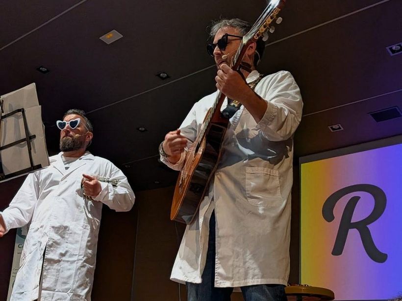Retórico e Hipotenuso en escena, con batas blancas y guitarra