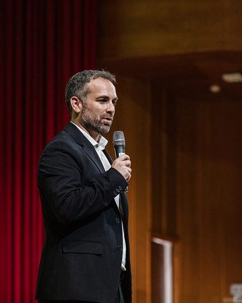 Santi García Cremades, con traje y micrófono, presentando en un teatro